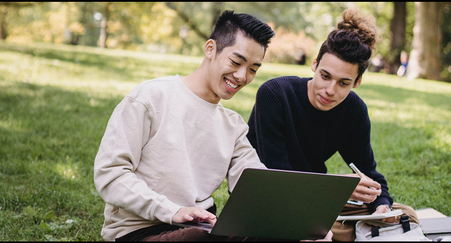 Deux étudiants issus de la diversité en train de lire de l'information sur l'assurance-emploi sur leur portable