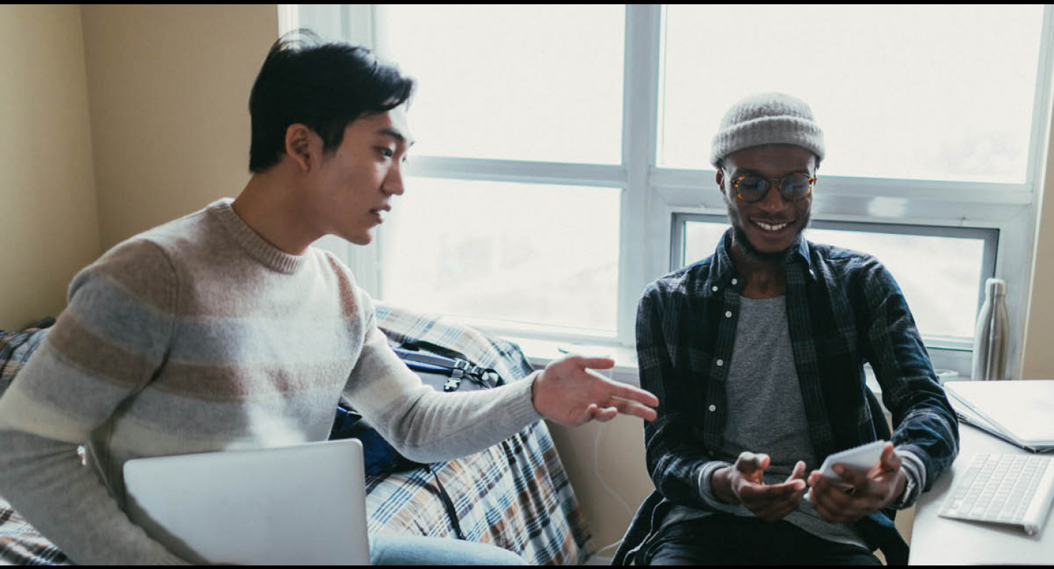 Deux colocs étudiants issus de la diversité en train de parler dans leur appartement