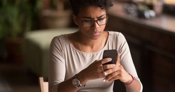 Une jeune femme qui fronce les sourcils devant son téléphone