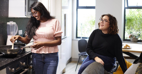 Deux colocs étudiantes, dont une issue de la diversité, en train de parler en cuisinant